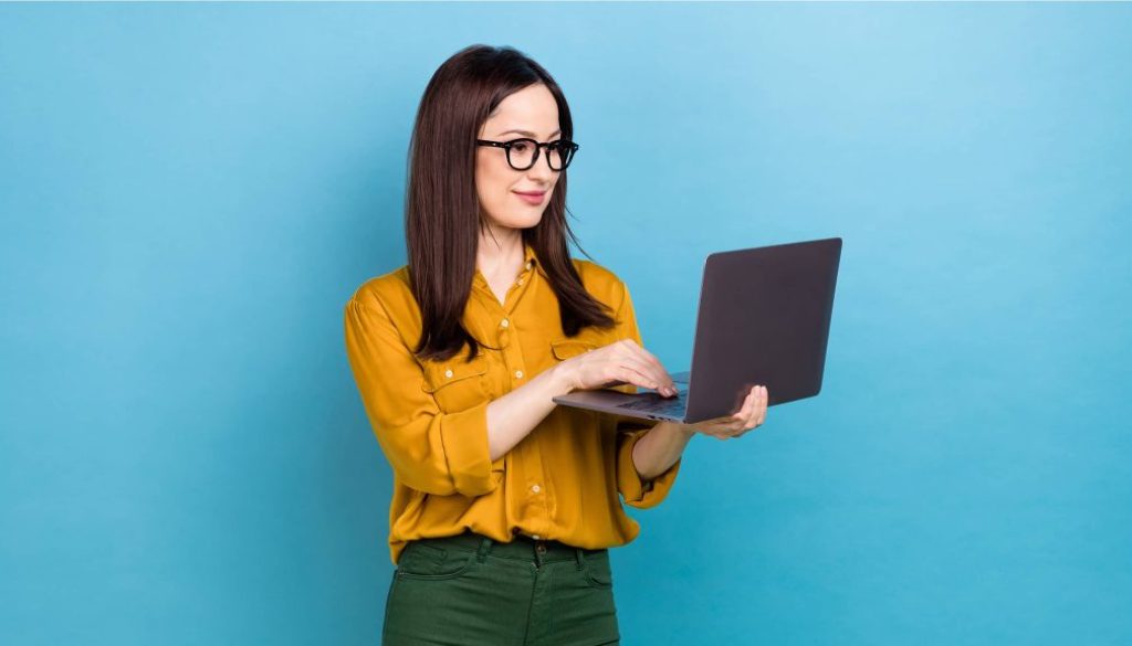 woman-glasses-standing-with-laptop-blue-background_2400x1350