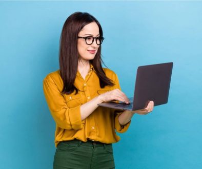 woman-glasses-standing-with-laptop-blue-background_2400x1350